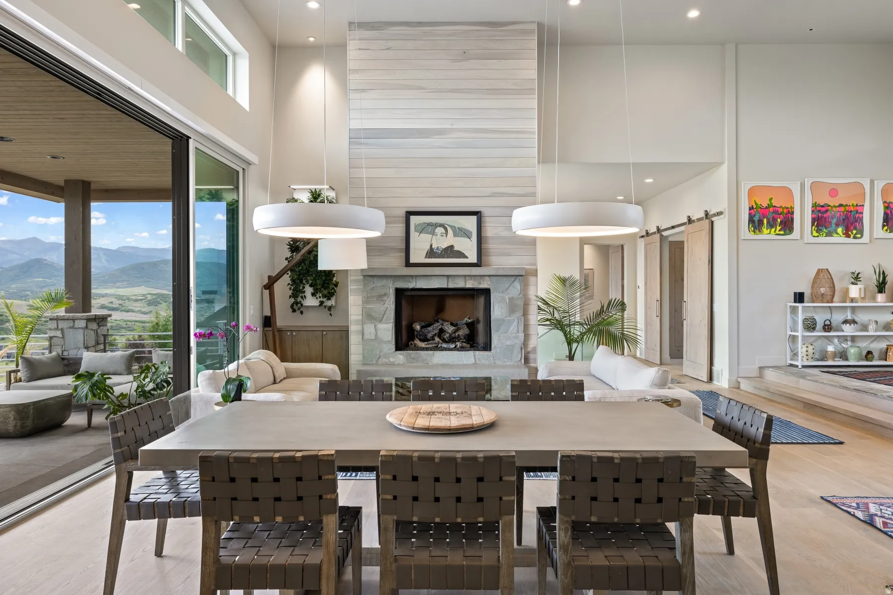 Dining room featuring a barn door, a towering ceiling, a premium fireplace, light wood-style floors, and a mountain view