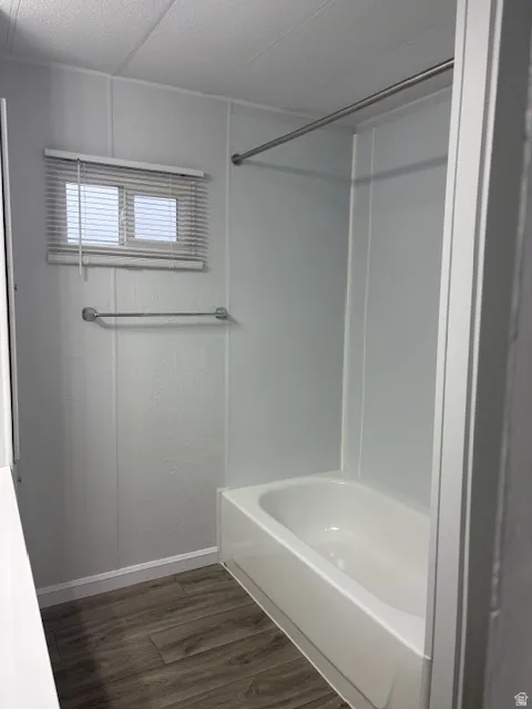 Full bathroom with dark wood-style floors and shower / tub combination