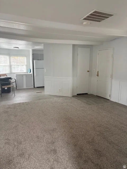 Unfurnished room featuring a decorative wall, a wainscoted wall, and light wood-style floors