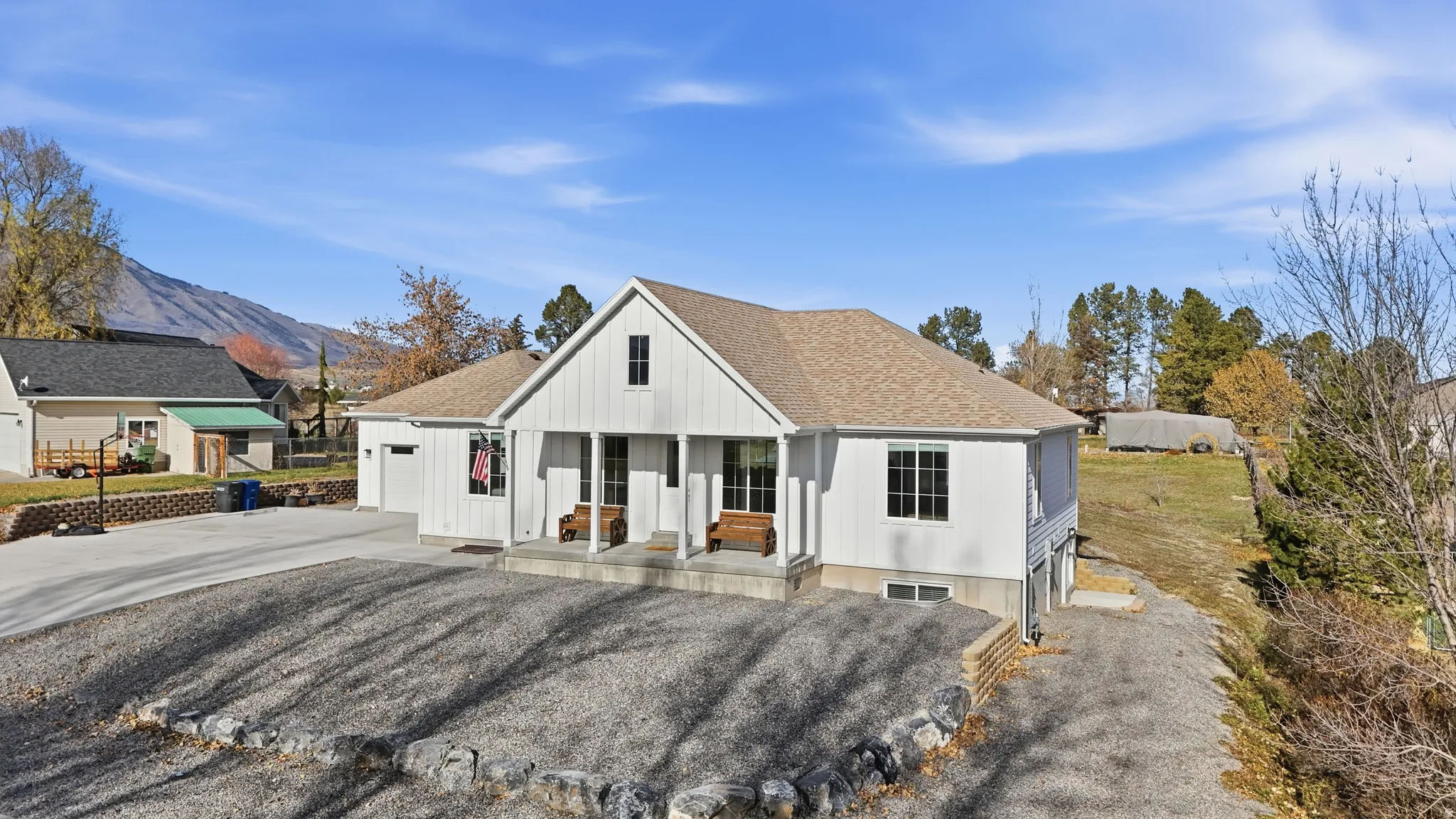 Modern farmhouse featuring a porch, driveway, roof with shingles, an attached garage, and a mountain view
