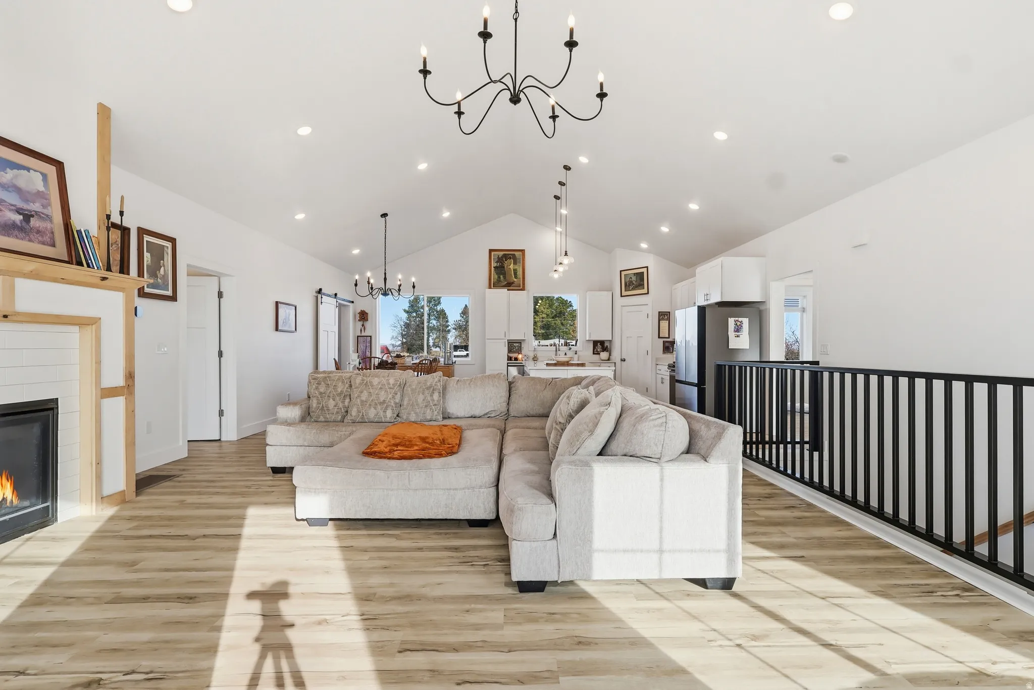 Living room featuring a chandelier, a tiled fireplace, light wood-type flooring, recessed lighting, and high vaulted ceiling