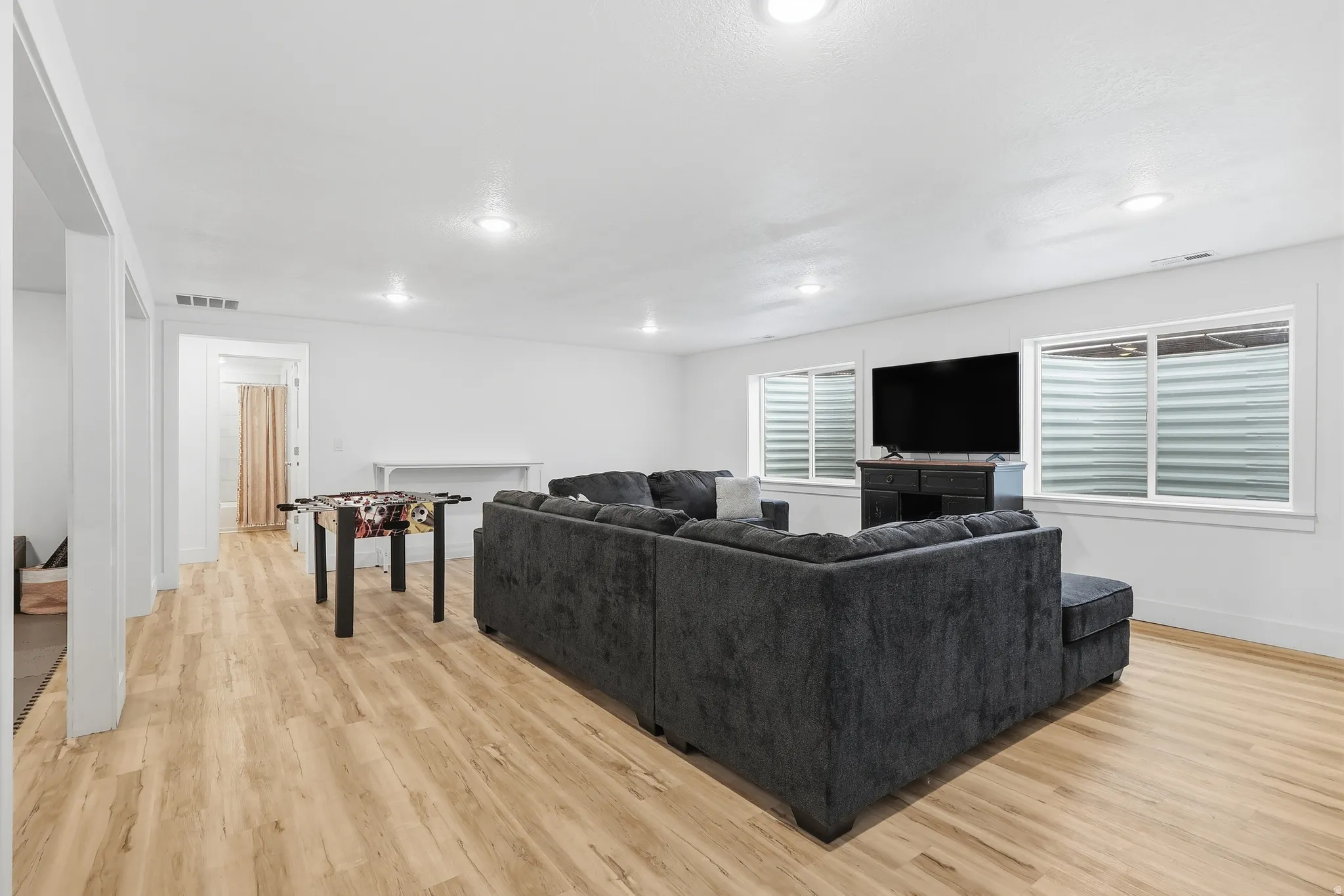 Living area with light wood-type flooring and recessed lighting
