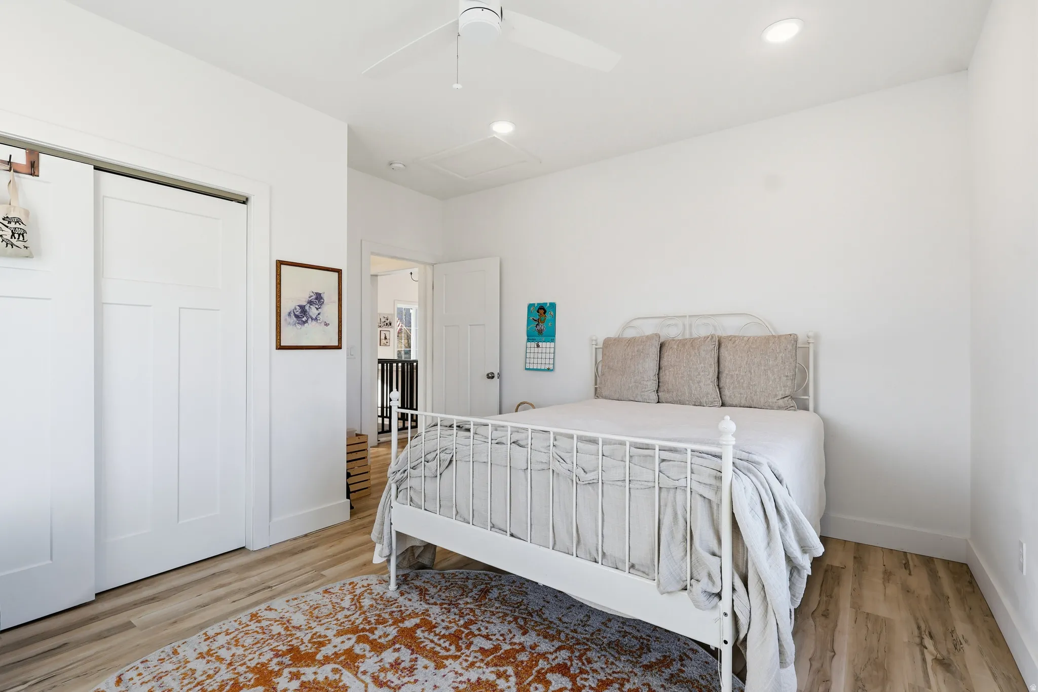 Bedroom with a closet, light wood finished floors, ceiling fan, attic access, and recessed lighting