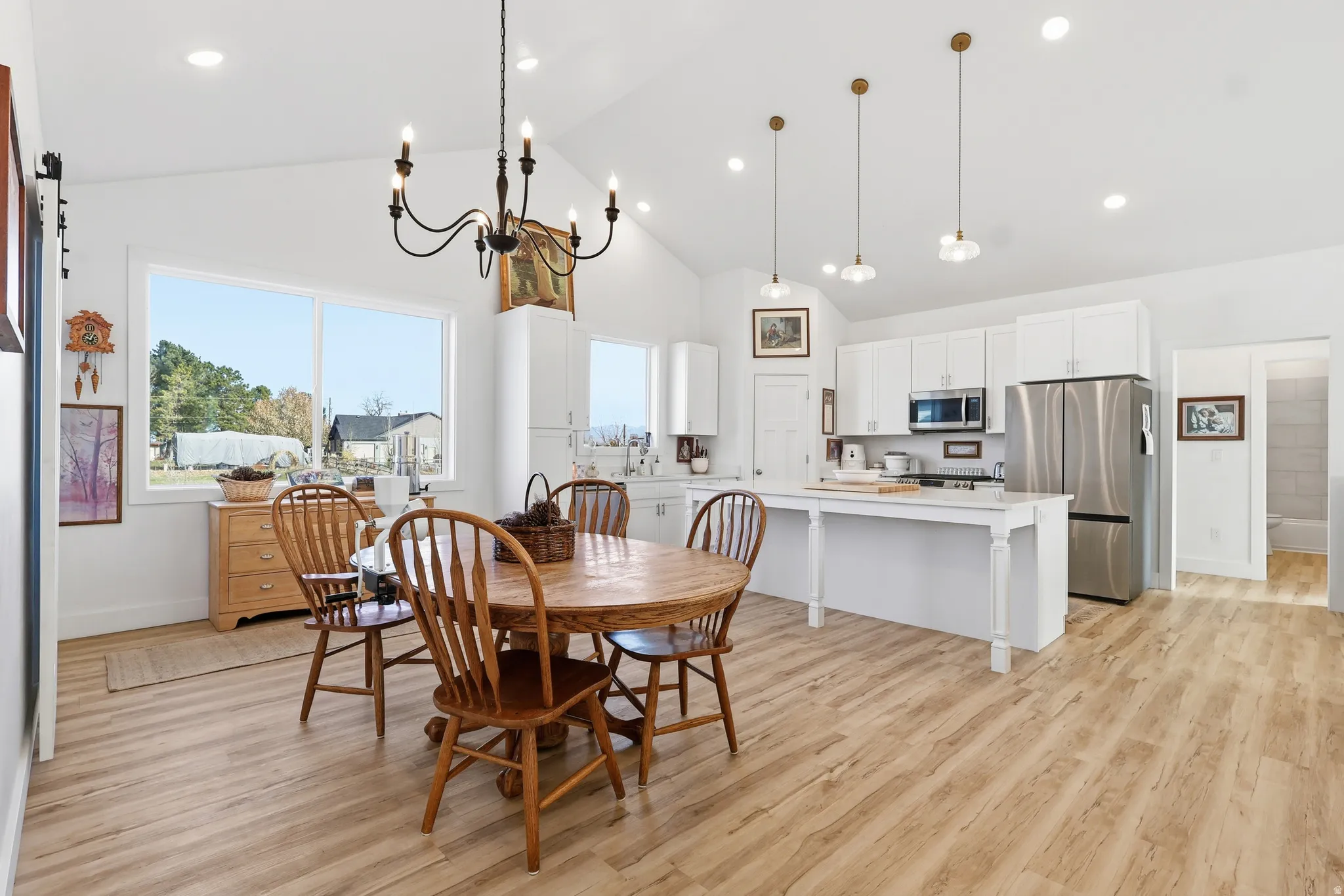 Dining room featuring high vaulted ceiling, recessed lighting, light wood-style flooring, and a chandelier