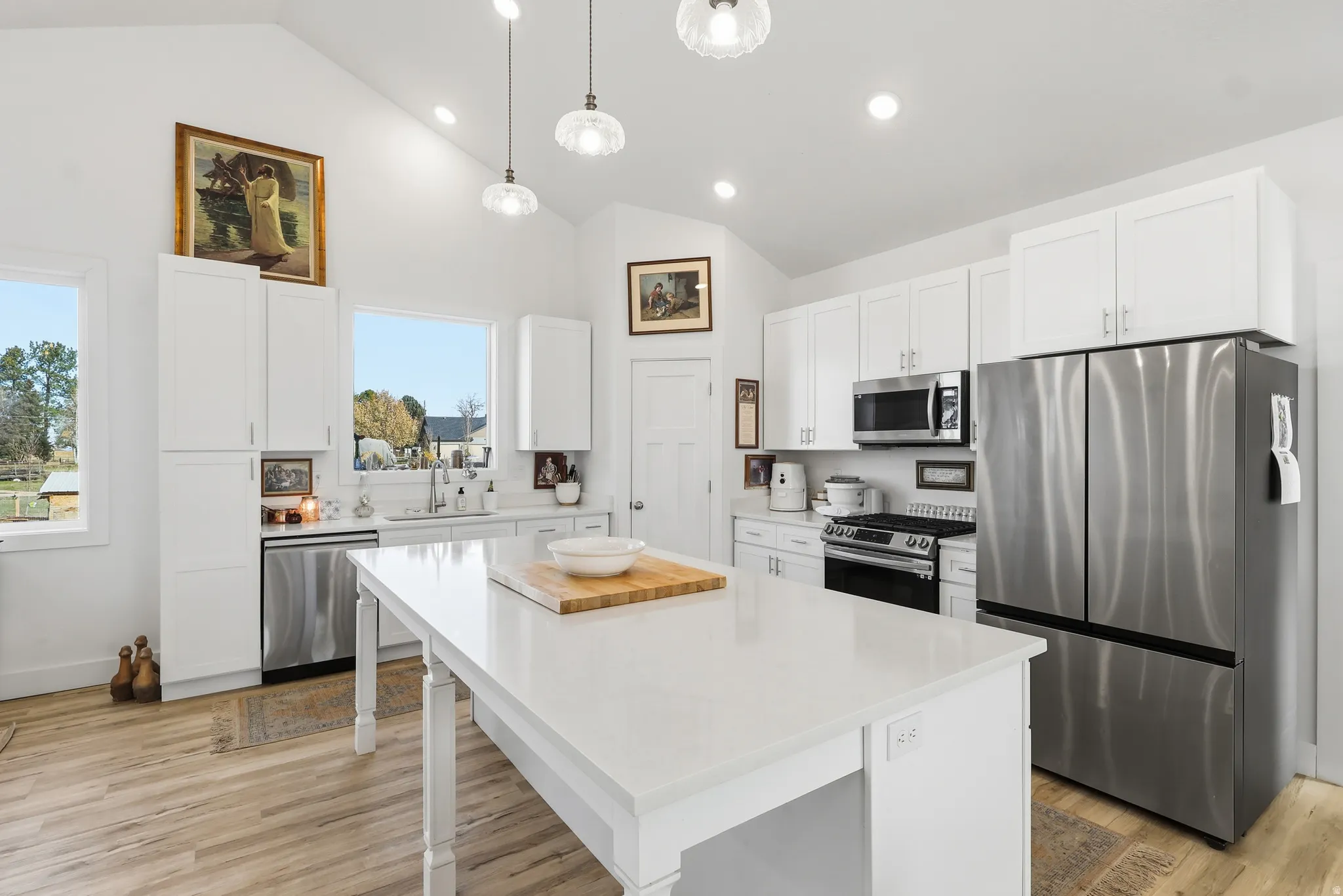 Kitchen featuring appliances with stainless steel finishes, white cabinetry, a center island, decorative light fixtures, and recessed lighting