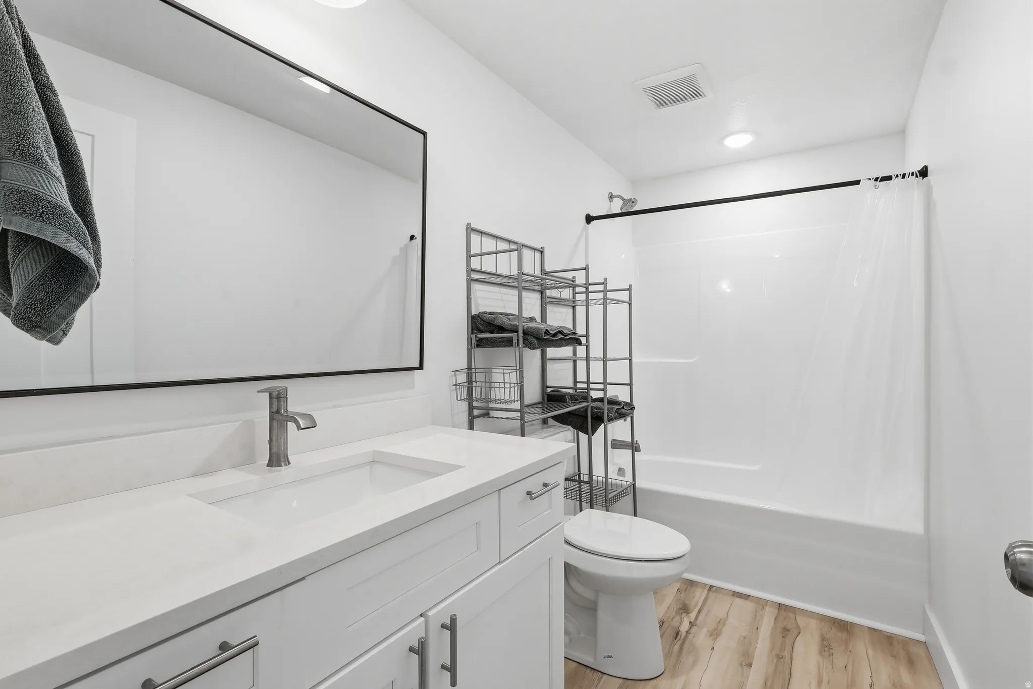 Full bath featuring vanity, shower / bathtub combination with curtain, and light wood-style flooring