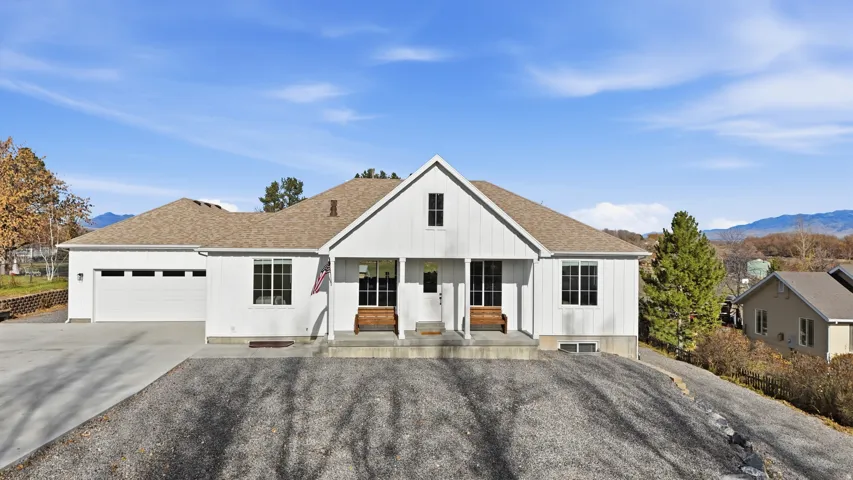 View of front facade featuring a porch, driveway, a shingled roof, and an attached garage