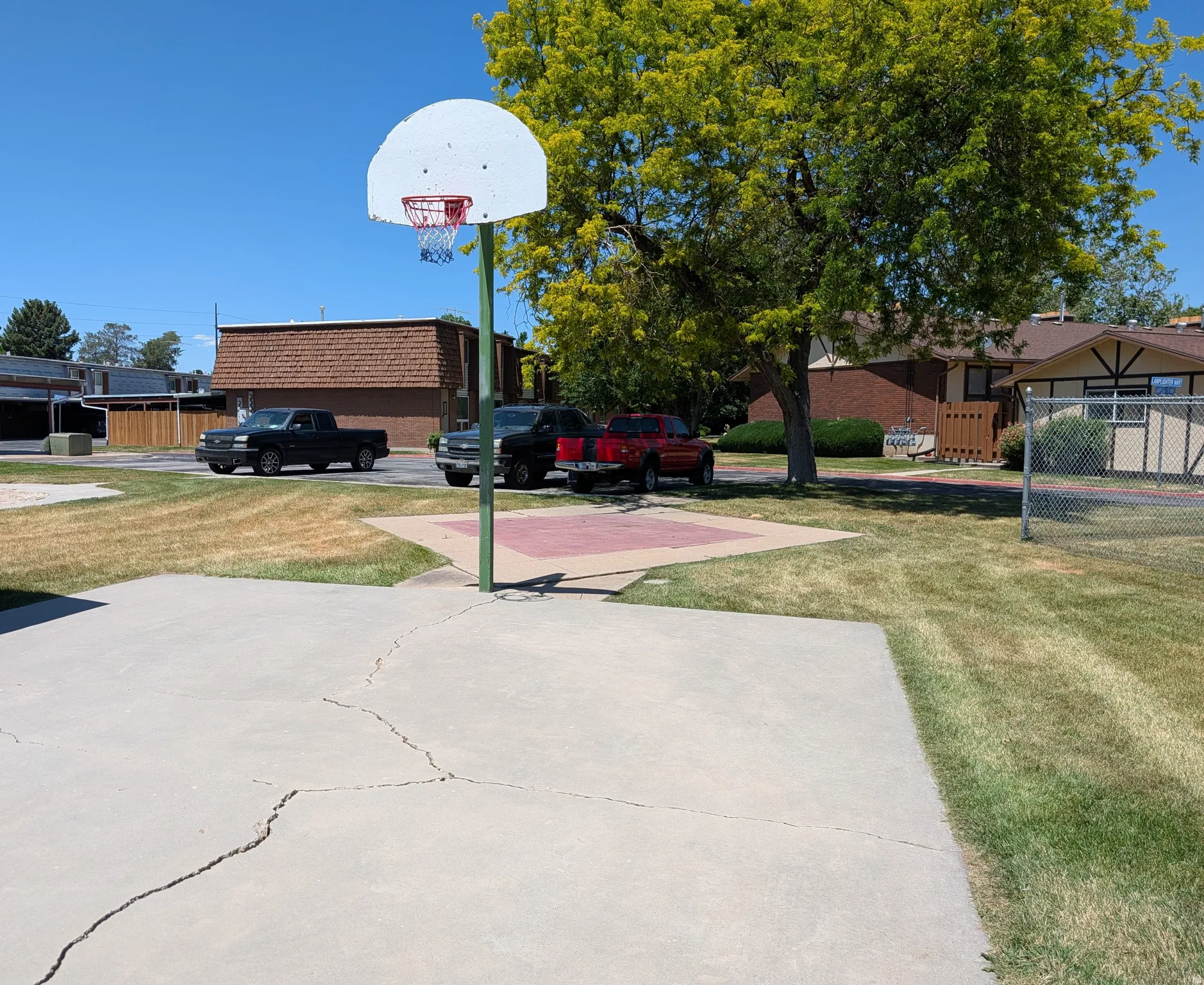 Outdoor concrete basketball court with a white backboard and red hoop