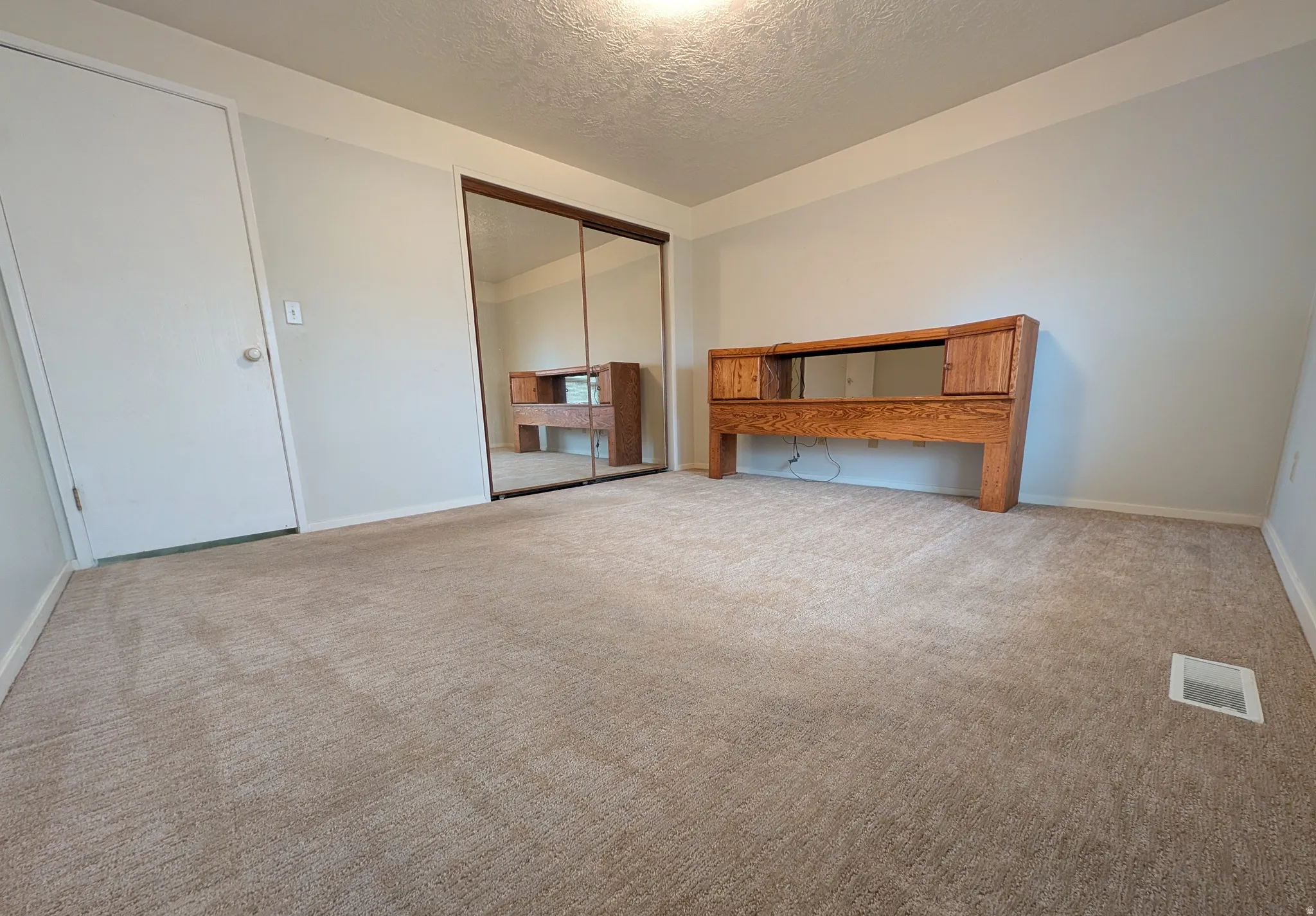 Unfurnished bedroom with a textured ceiling, a closet, and carpet flooring