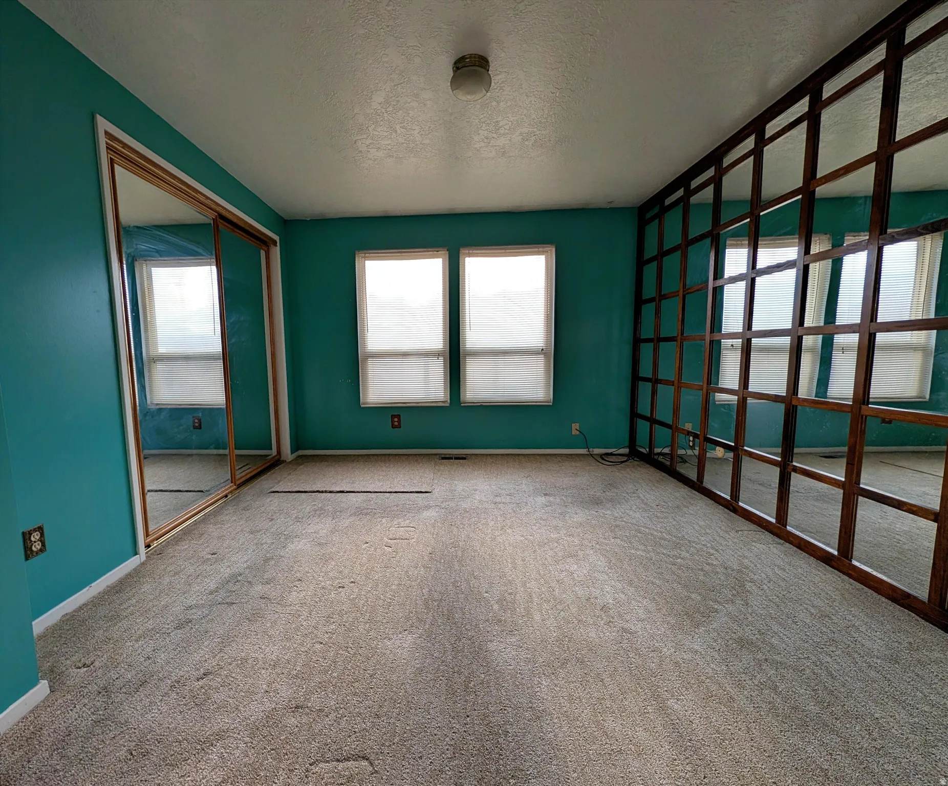 Bedroom with a textured ceiling, carpet and Mirrors