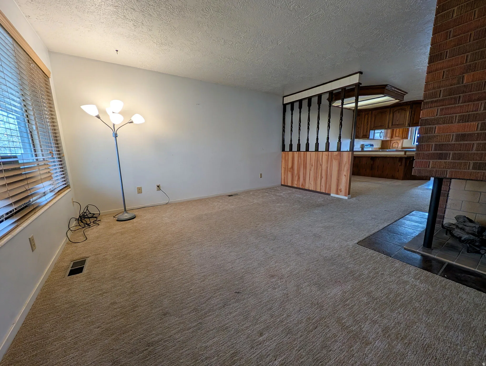 Unfurnished living room featuring a textured ceiling, carpet floors, and a fireplace