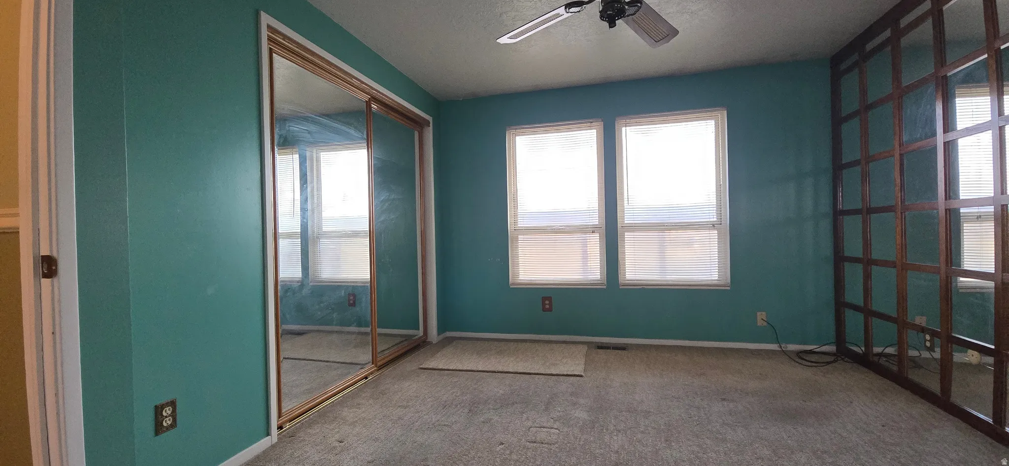 Carpeted empty room with ceiling fan and baseboards