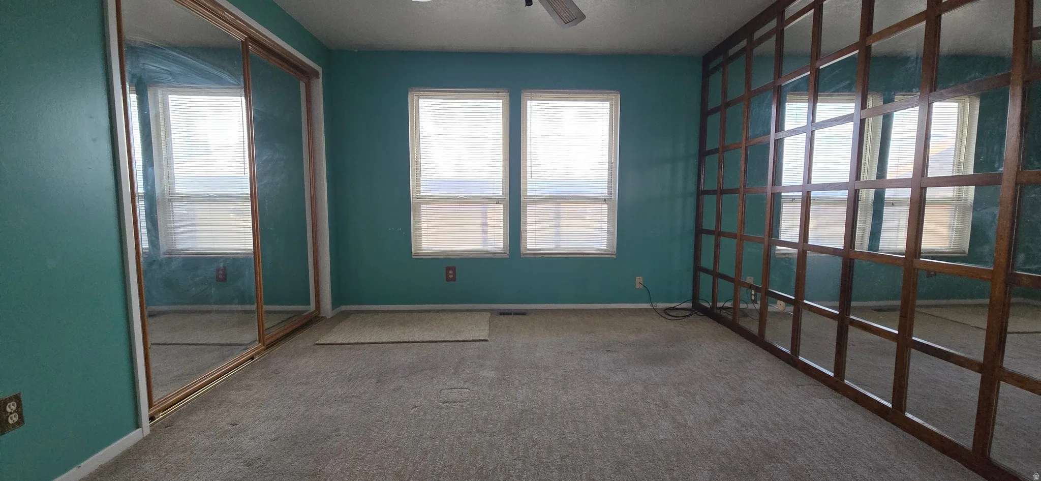 Carpeted spare room featuring ceiling fan and baseboards