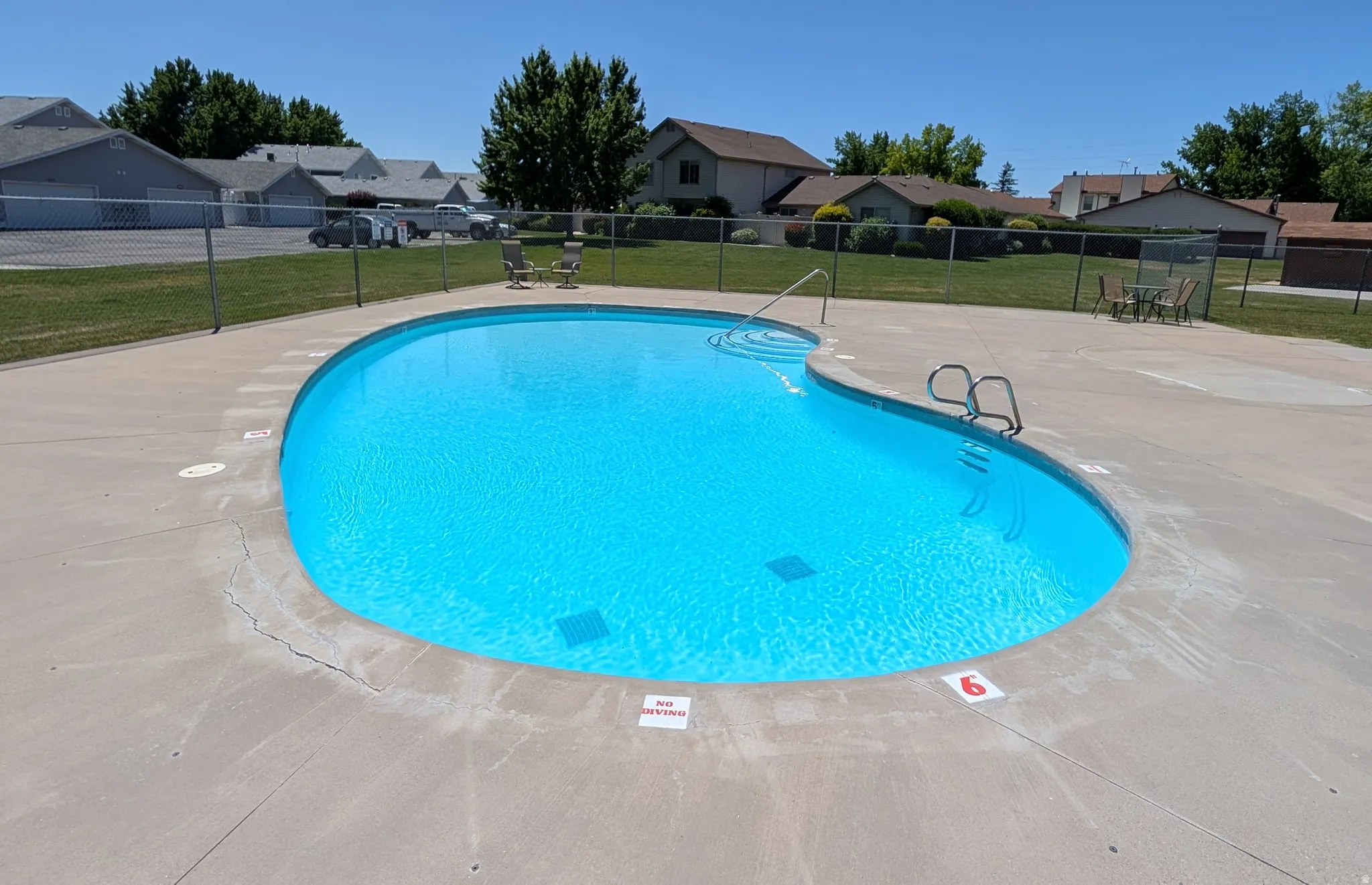 Curved swimming pool with light blue water surrounded by a concrete deck