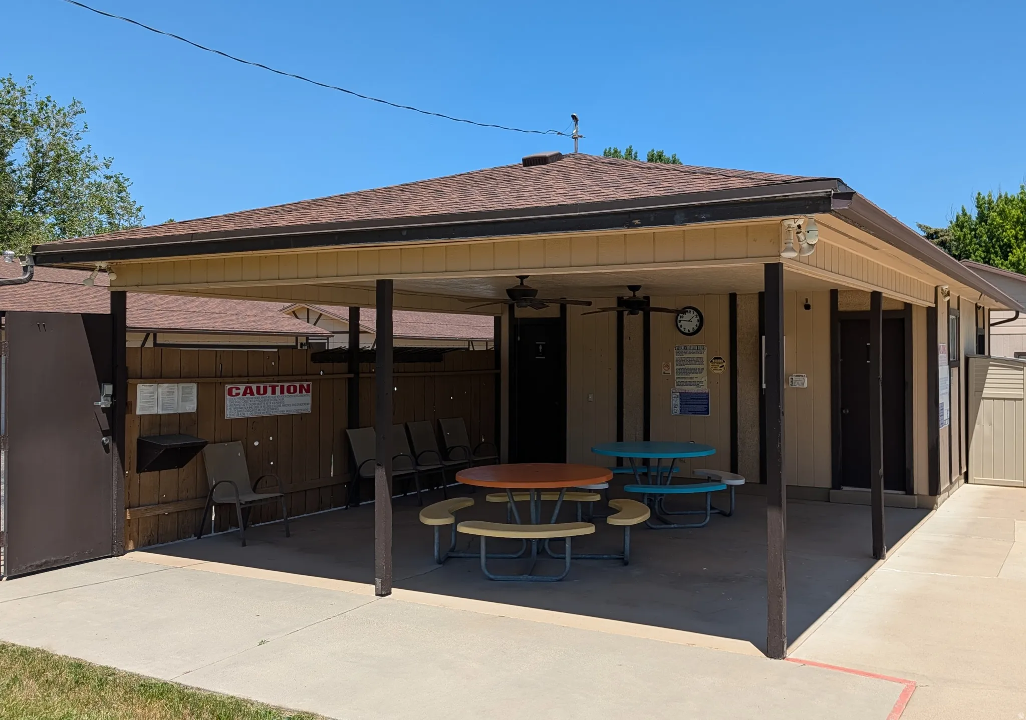 Covered patio area featuring a brown shingle roof, beige siding, and dark support pillars