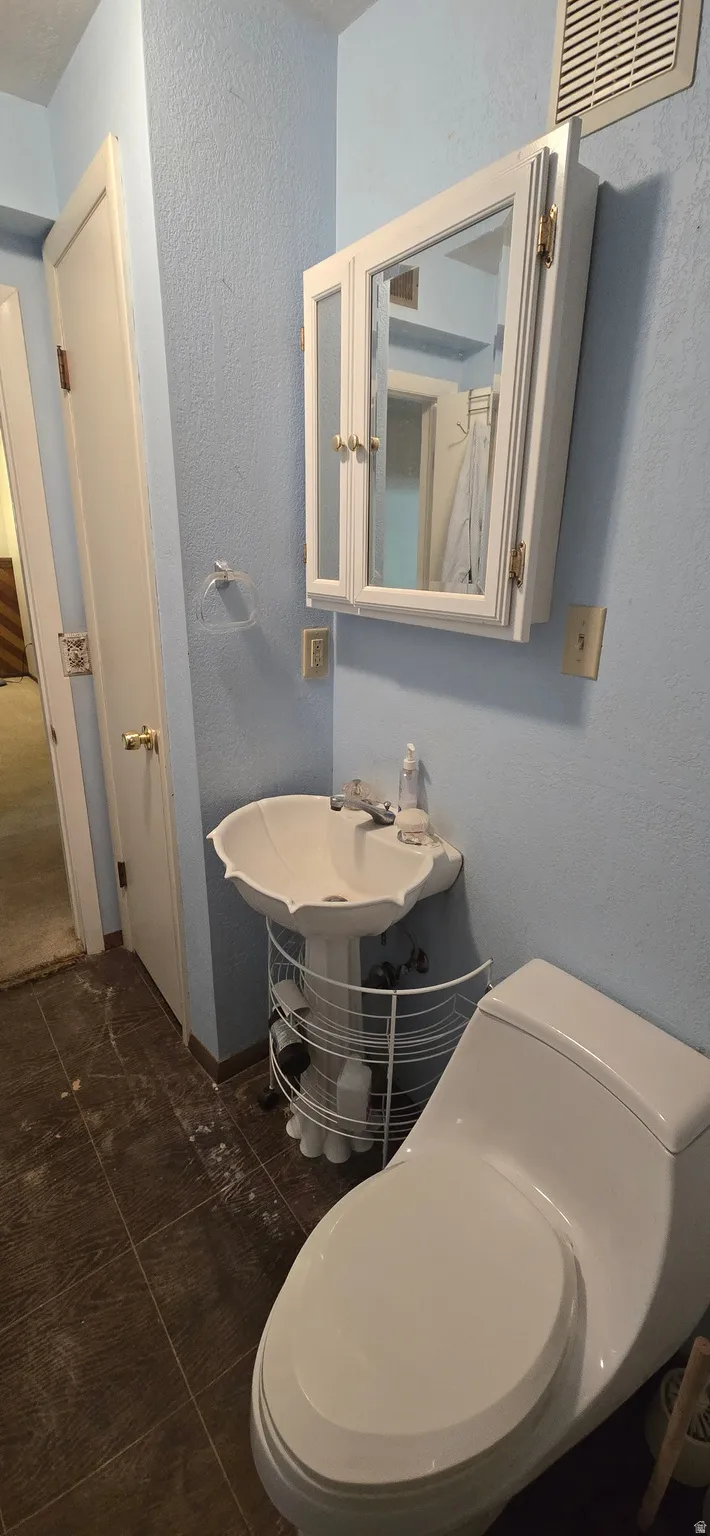 Bathroom featuring a textured wall and dark tile patterned floors