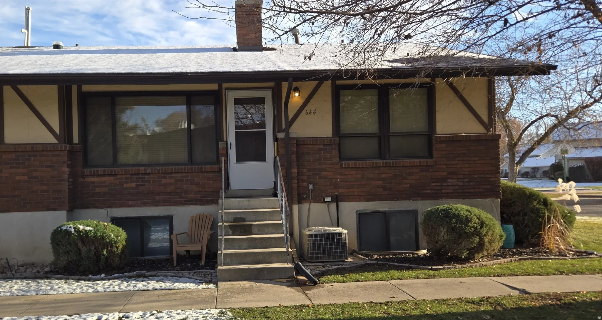 View of front of property with brick siding, a chimney, and entry steps