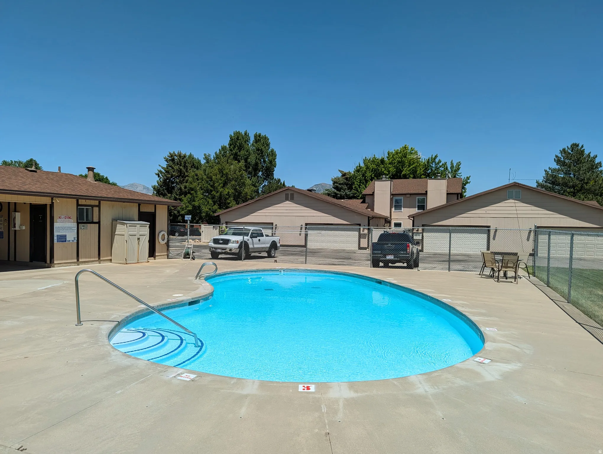 Inviting swimming pool with concrete decking, featuring graduated steps for entry and metal handrails