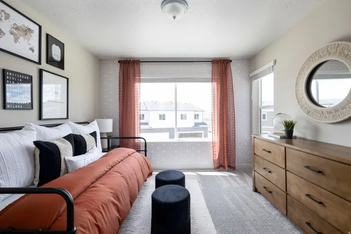 Bedroom with a textured ceiling, wallpapered walls, light colored carpet, and an accent wall