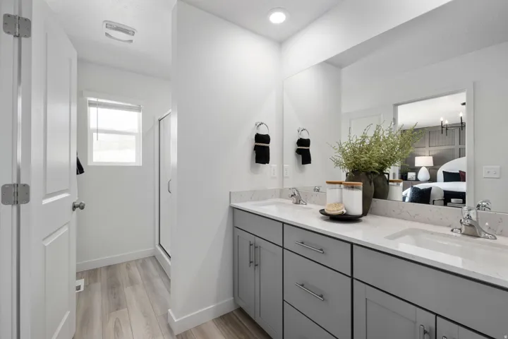 Full bath featuring double vanity, light wood-type flooring, ensuite bath, and a shower stall