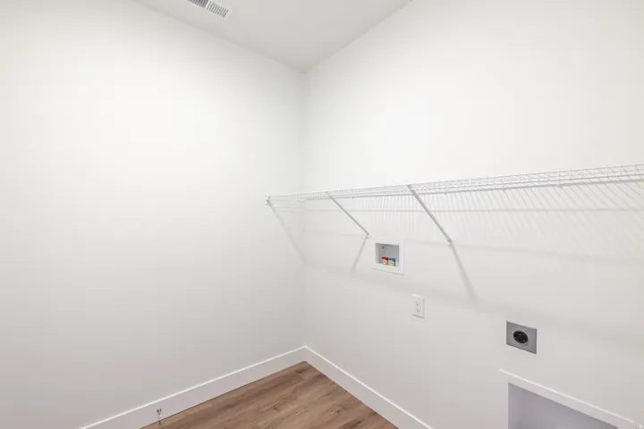 Dedicated utility space featuring wood-finish flooring, white walls, and a wire shelving unit