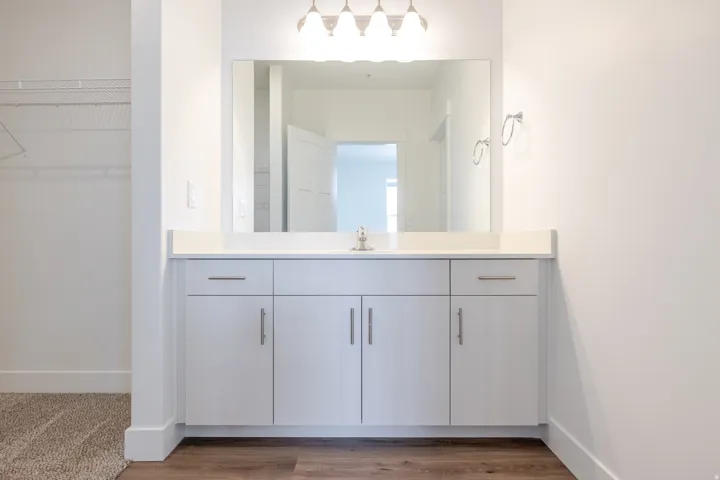 Vanity with white cabinetry, a light-toned countertop, and a rectangular wall-mounted mirror
