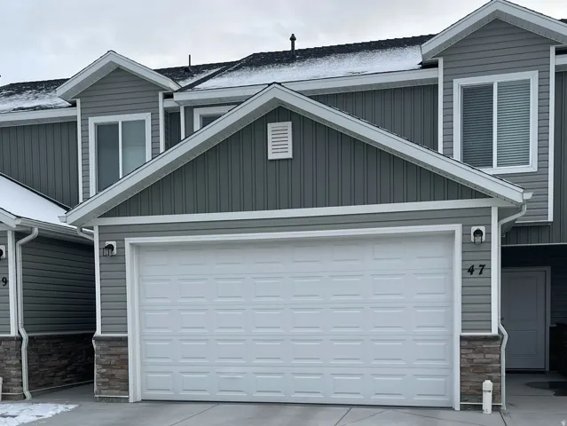 View of front facade with stone siding, concrete driveway, an attached garage, and board and batten siding