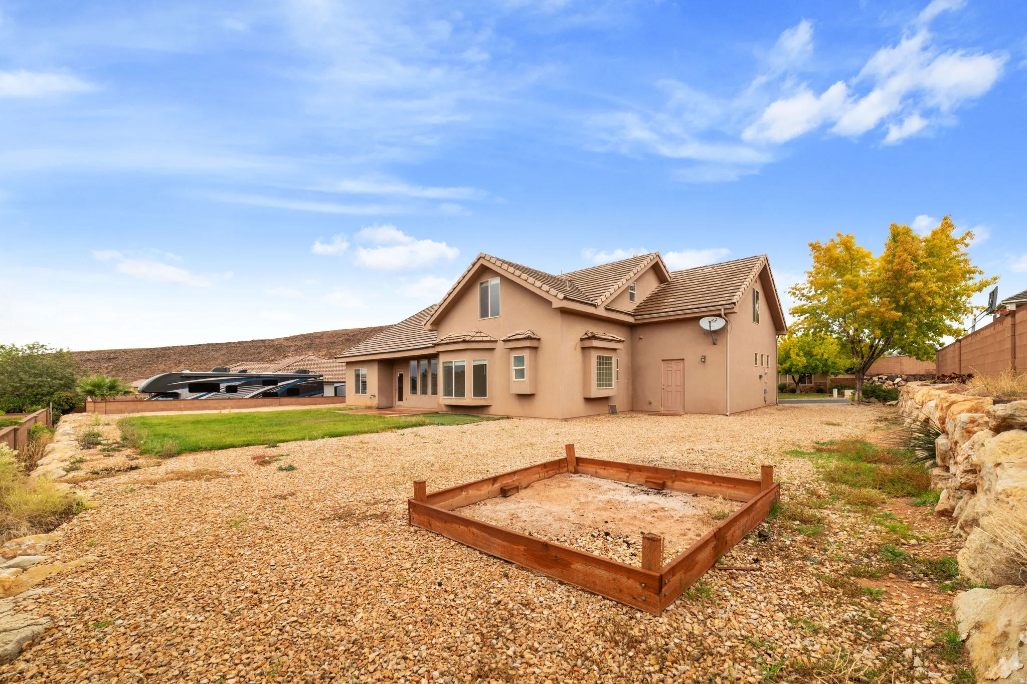 Rear view of house featuring stucco siding, a tile roof, and a vegetable garden