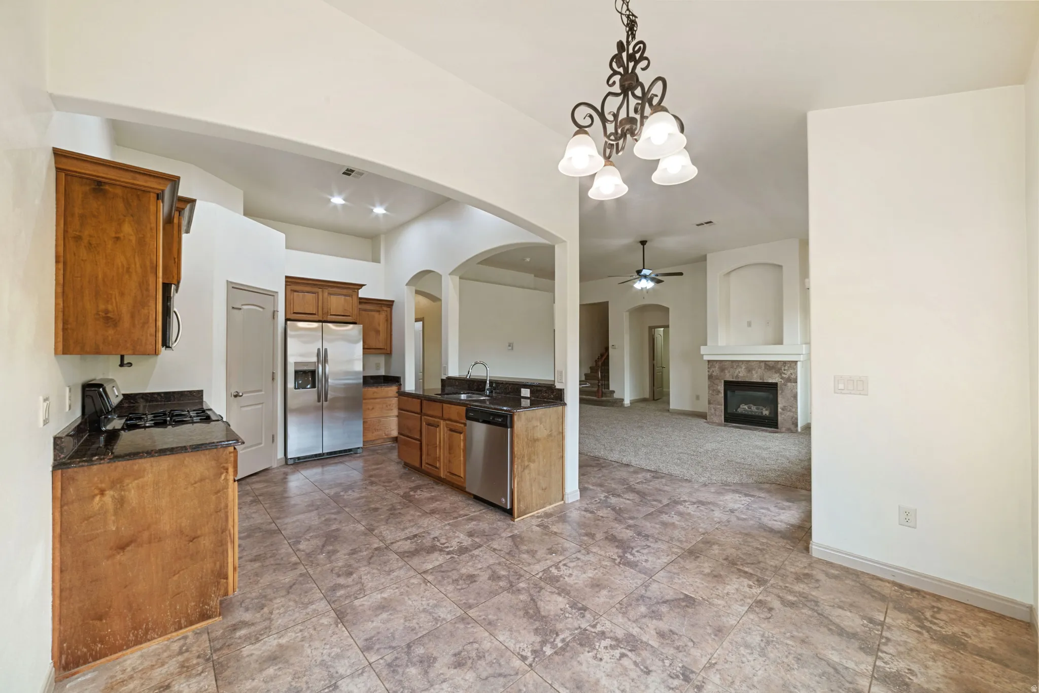 Kitchen with arched walkways, decorative light fixtures, a chandelier, appliances with stainless steel finishes, and open floor plan
