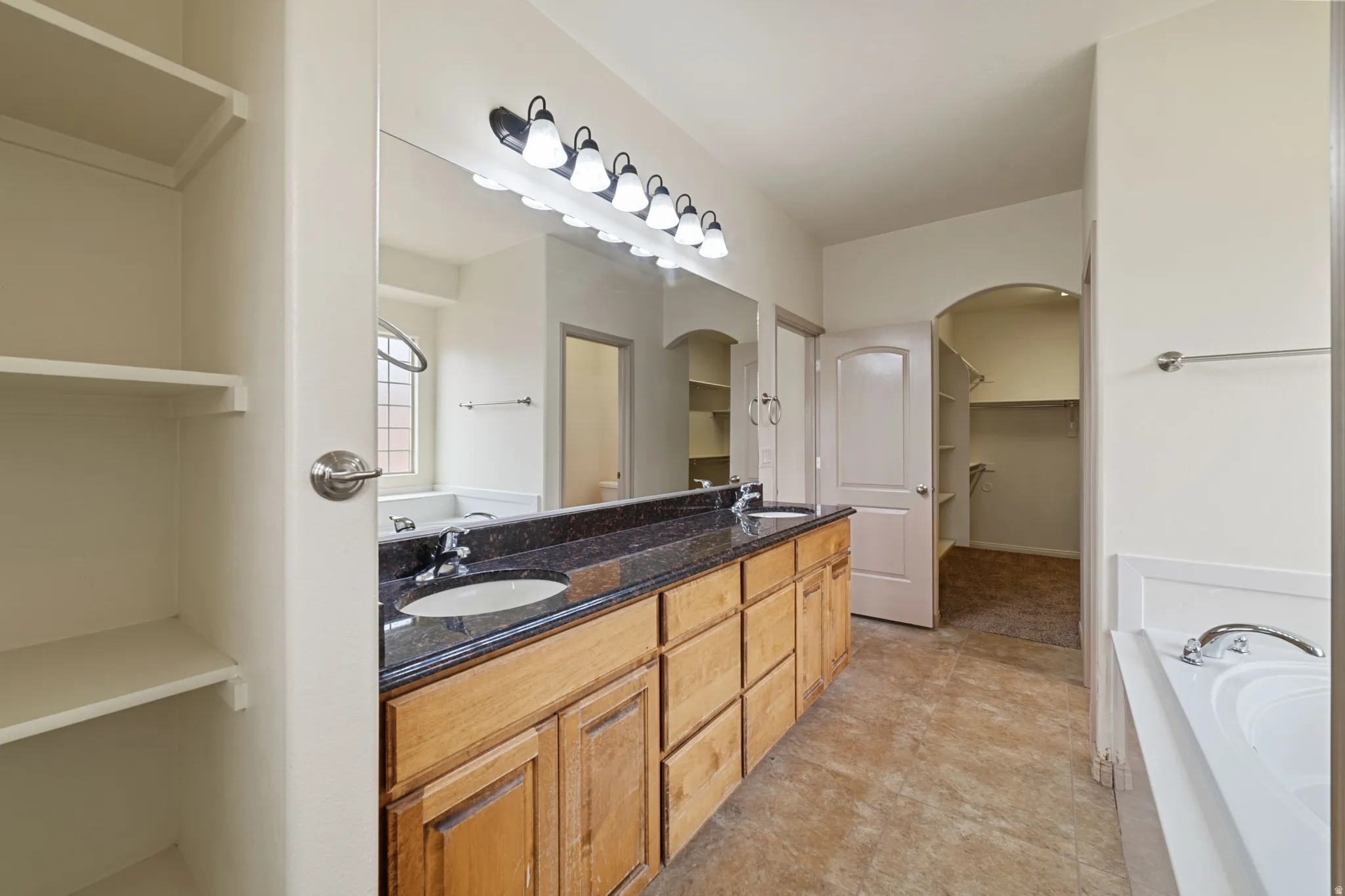 Bathroom with a bath, a spacious closet, and double vanity