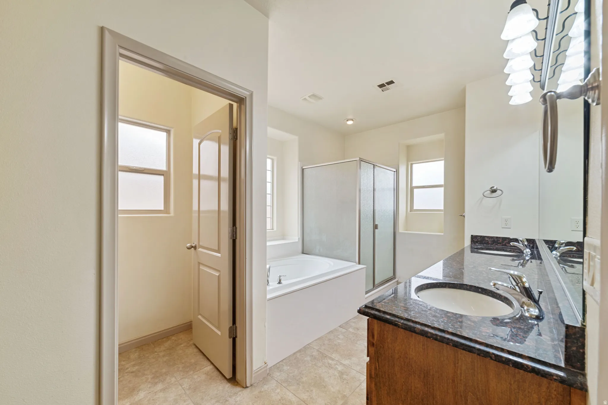 Full bathroom with a bath, a shower stall, double vanity, and light tile patterned floors
