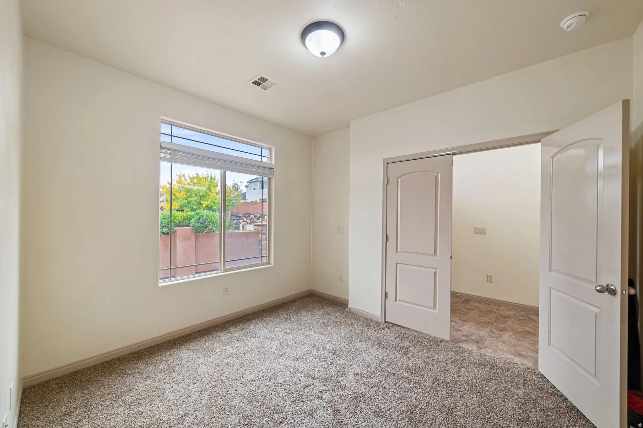 Unfurnished bedroom with light colored carpet and baseboards