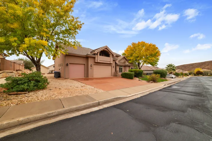 View of front facade featuring driveway, a tiled roof, stucco siding, and a garage