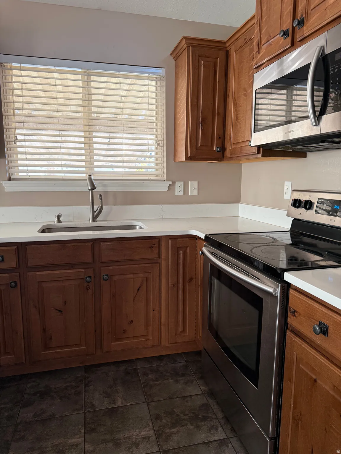 Kitchen with stainless steel appliances, brown cabinets, and light countertops