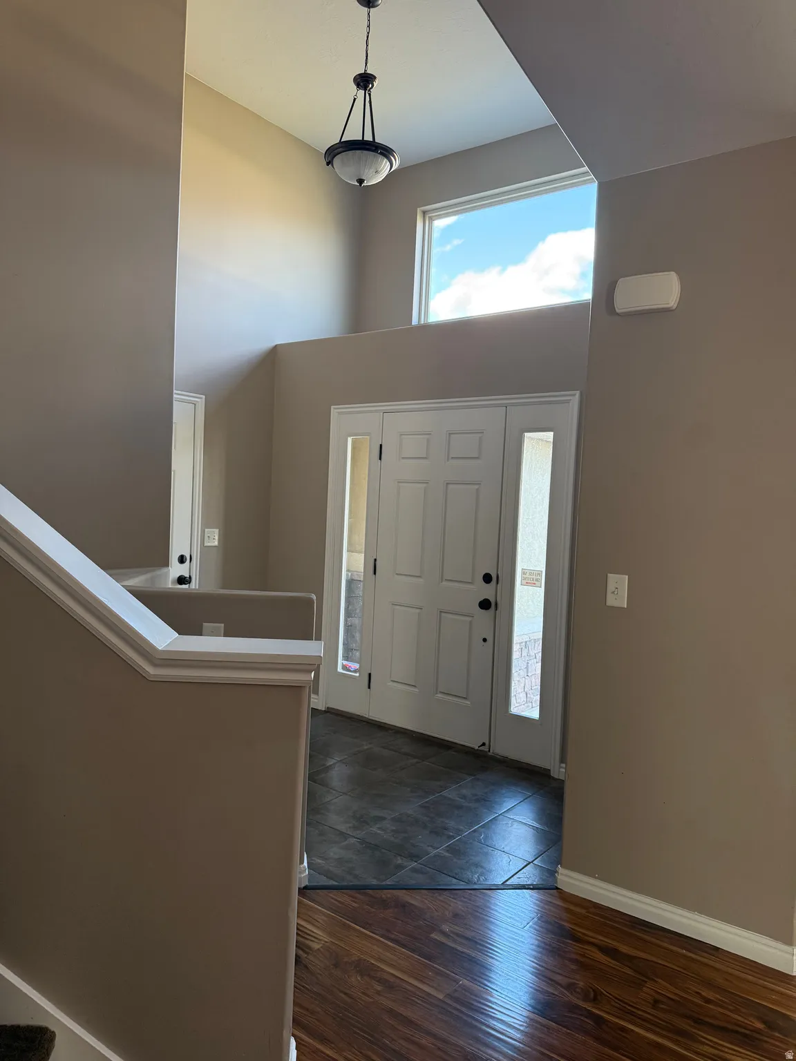 Entrance foyer featuring a towering ceiling, dark wood-type flooring, and stairway