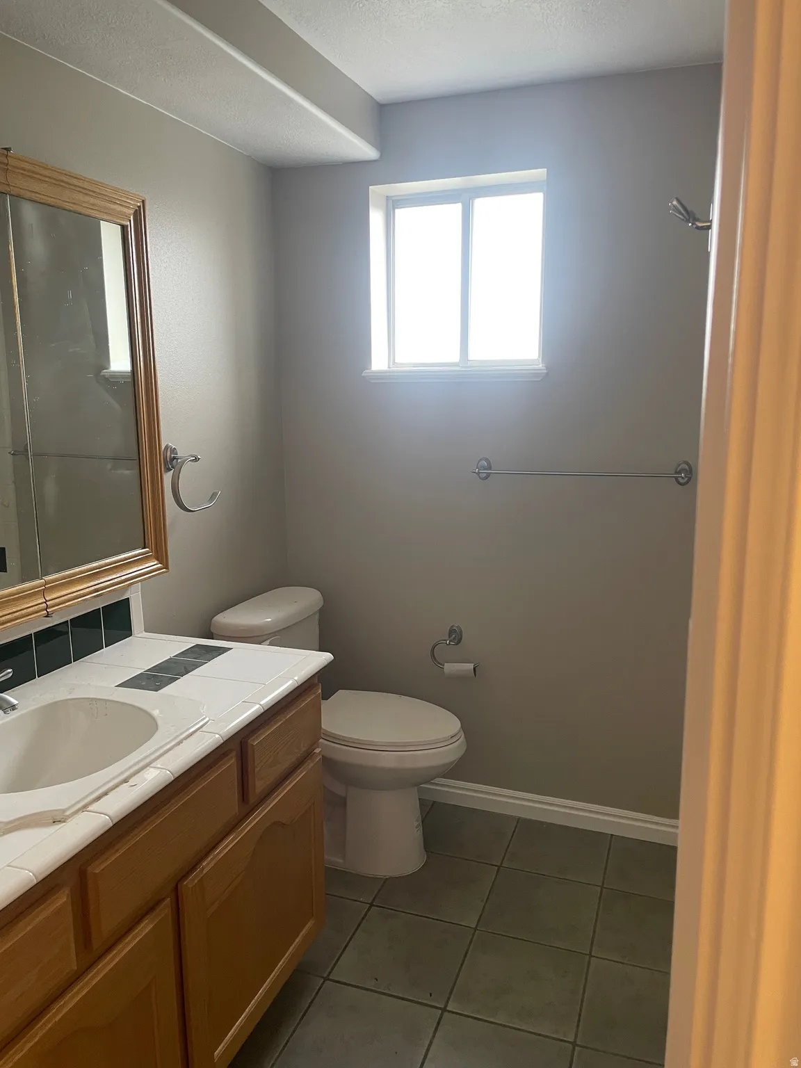 Bathroom featuring vanity, dark tile patterned flooring, and a textured ceiling