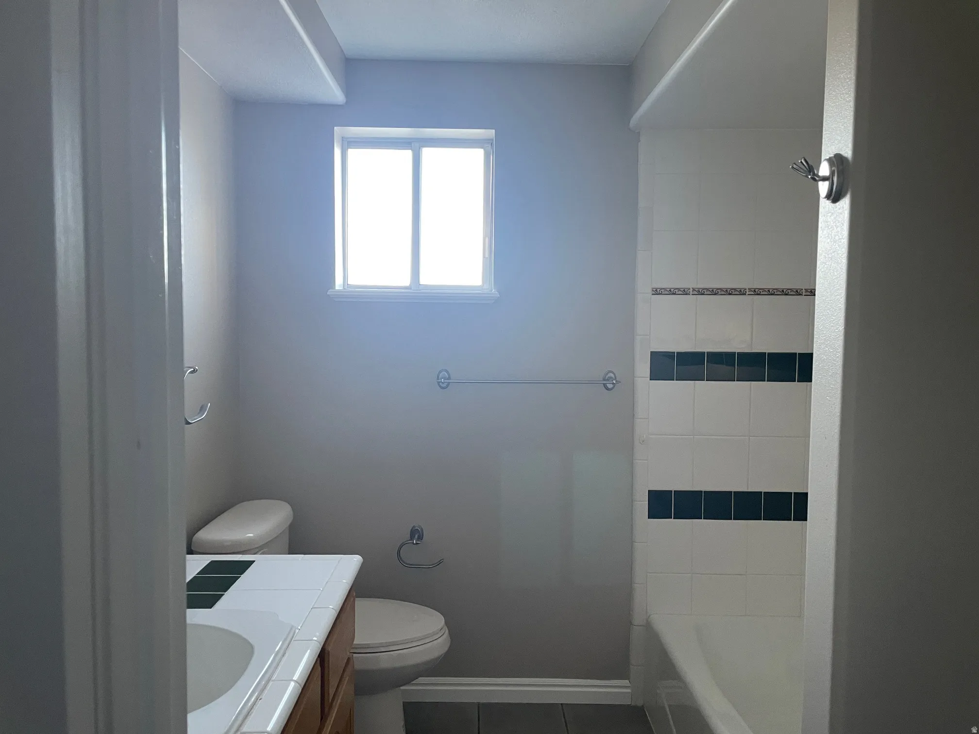 Full bathroom with vanity, dark tile patterned floors, and shower / bathtub combination