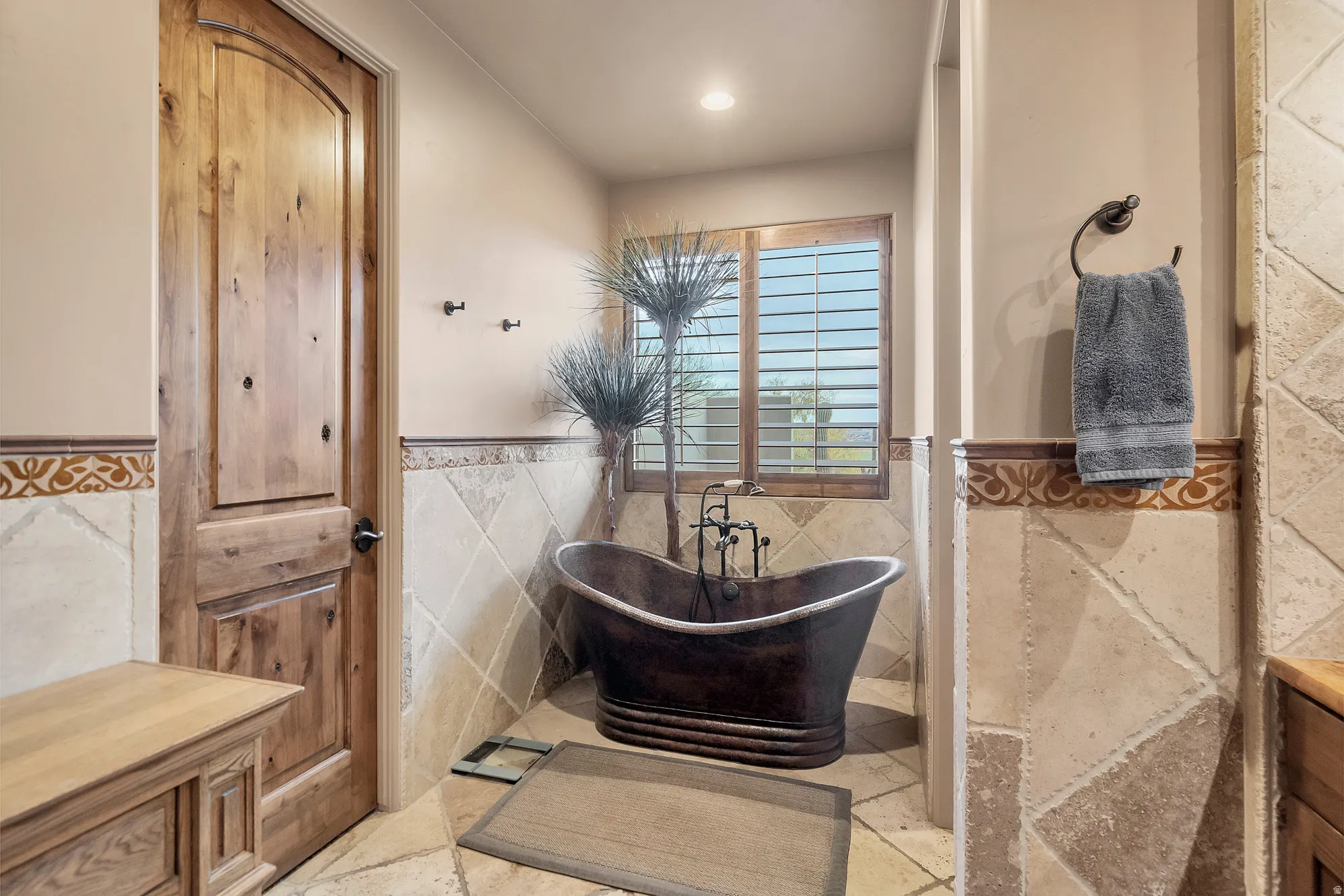 Full bath with a wainscoted wall, a soaking tub, and tile walls