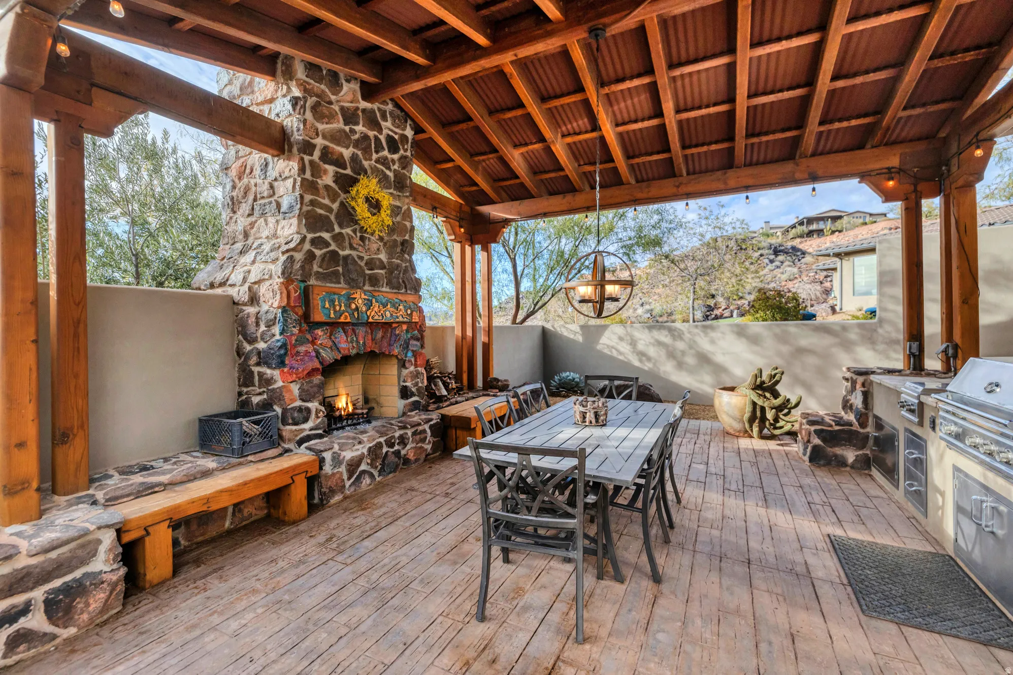 Wooden deck with outdoor dining area, area for grilling, and an outdoor stone fireplace