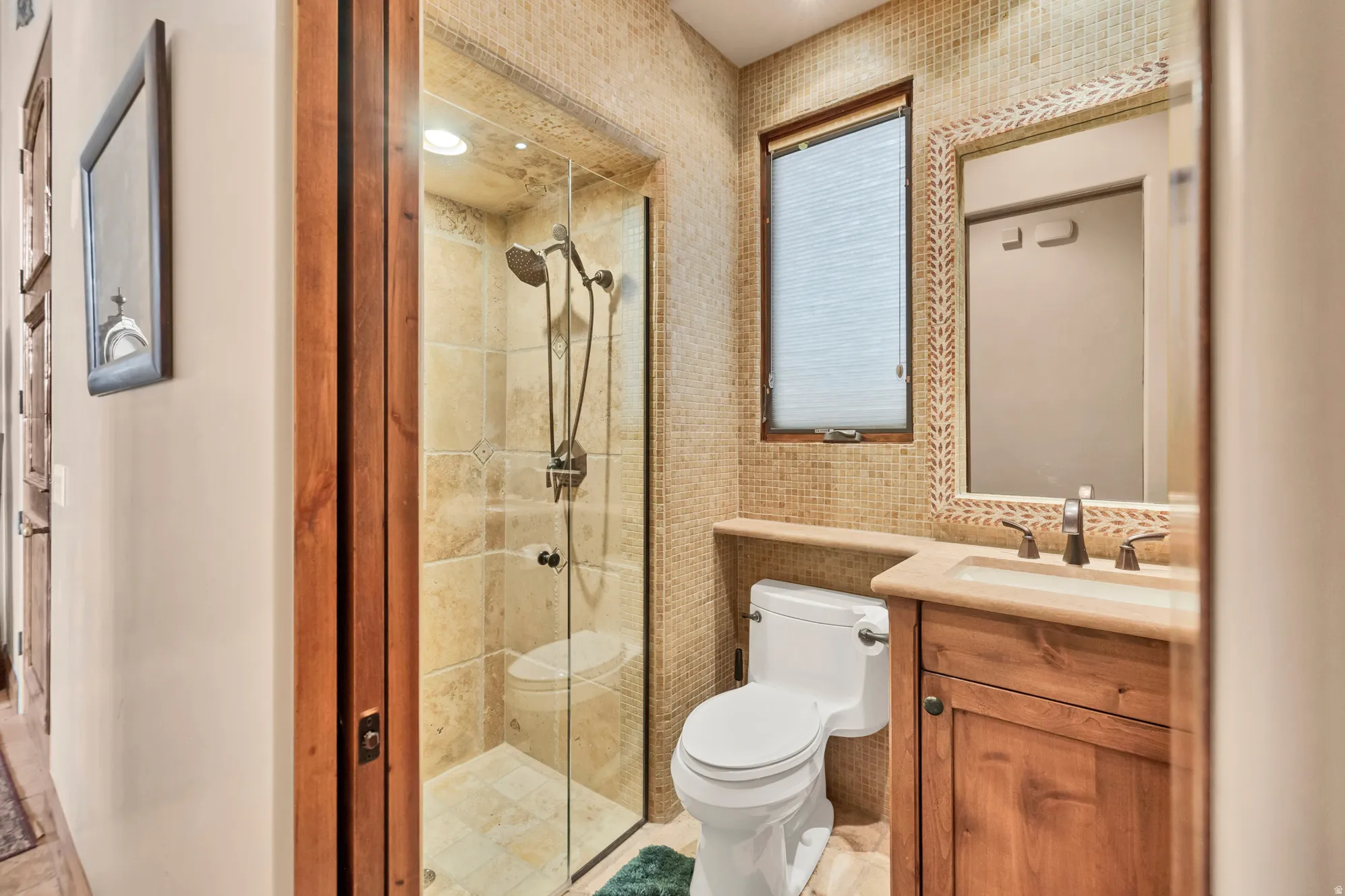 Full bath featuring vanity, a shower stall, and tile walls