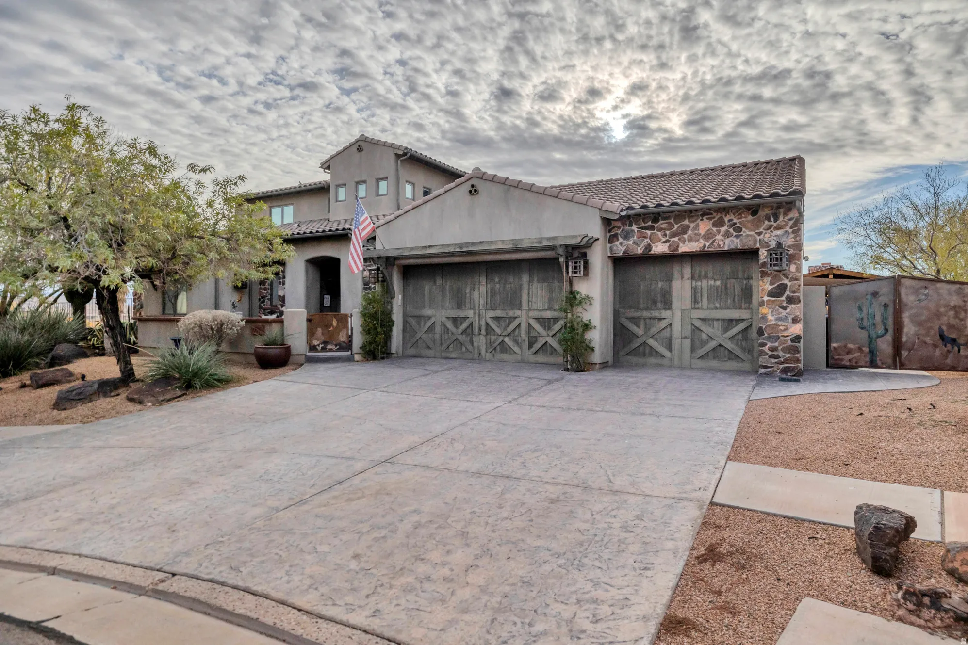 Mediterranean / spanish home with an attached garage, driveway, stone siding, and a tile roof