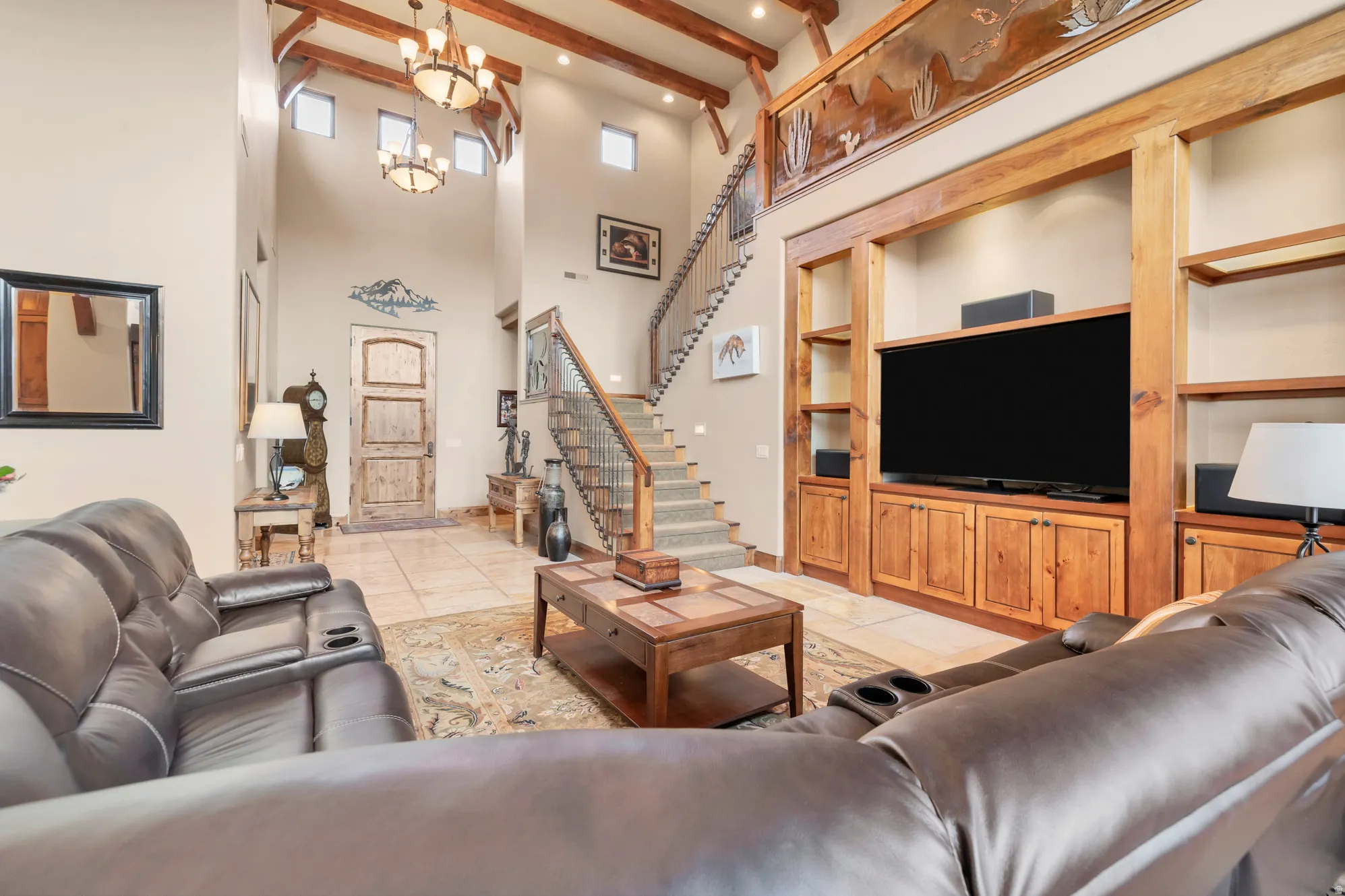 Living room featuring built in features, light tile patterned flooring, beamed ceiling, a high ceiling, and stairs
