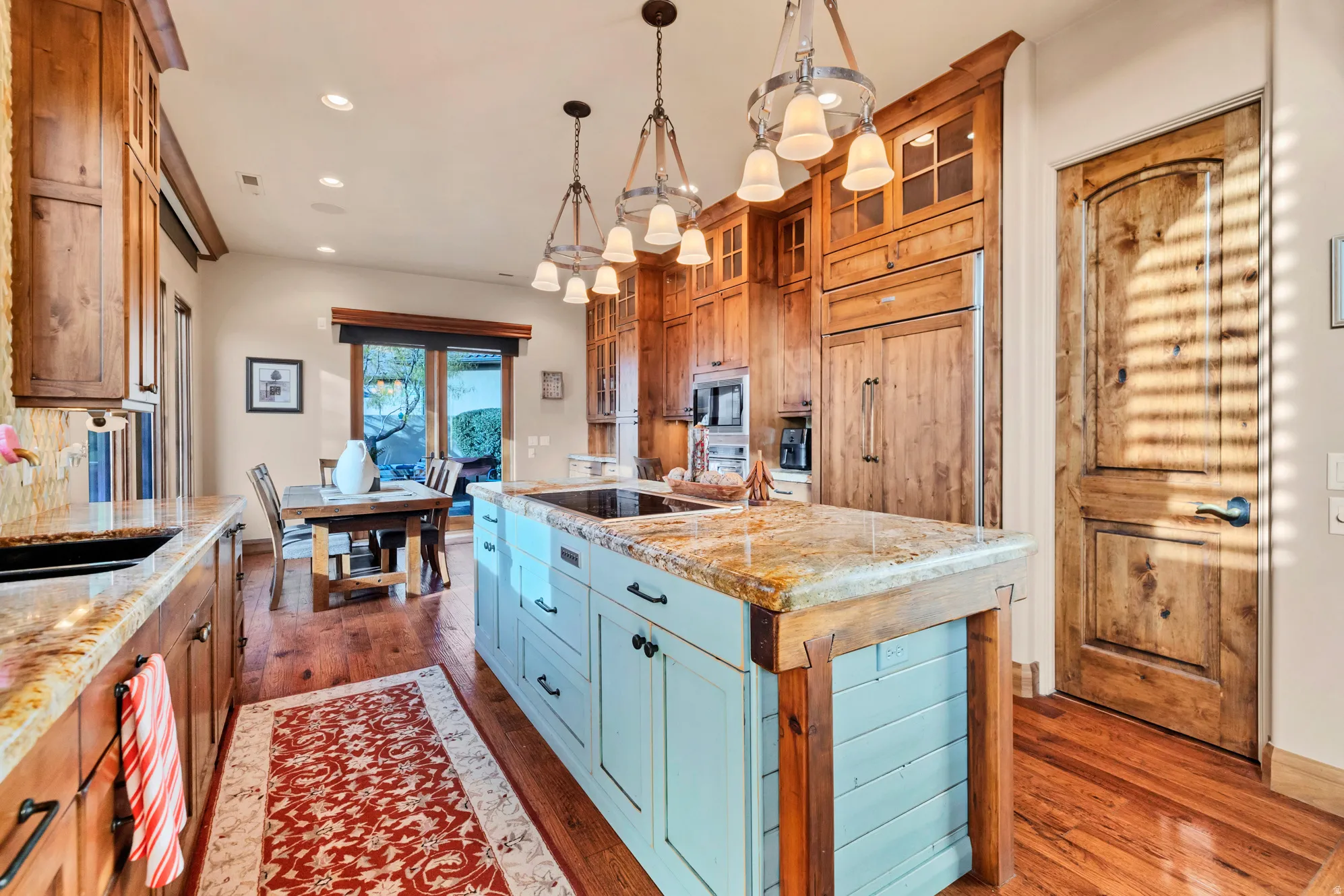 Kitchen featuring a kitchen island, recessed lighting, dark wood-style floors, glass insert cabinets, and decorative light fixtures