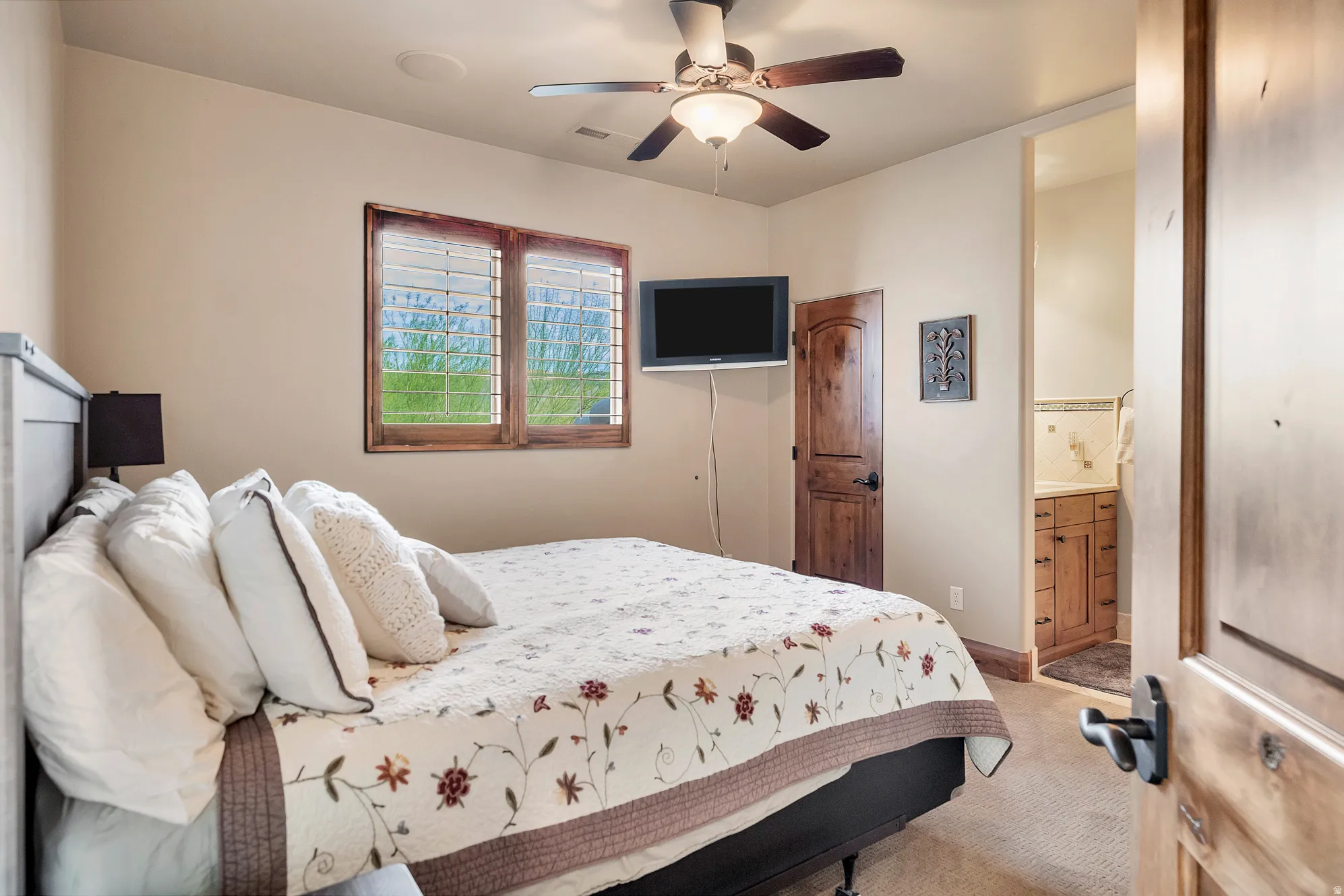 Bedroom with carpet floors, a ceiling fan, and ensuite bath