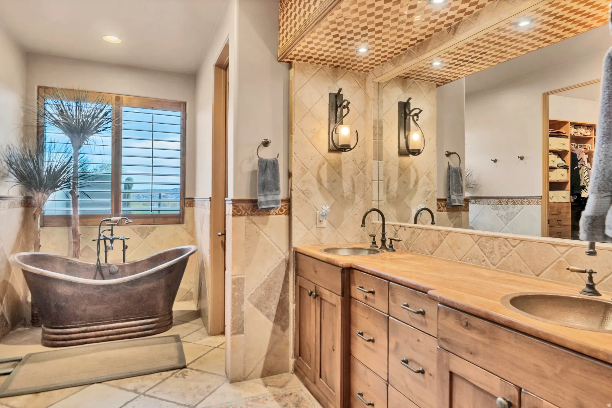 Full bathroom with double vanity, a freestanding bath, tile walls, a wainscoted wall, and a walk in closet