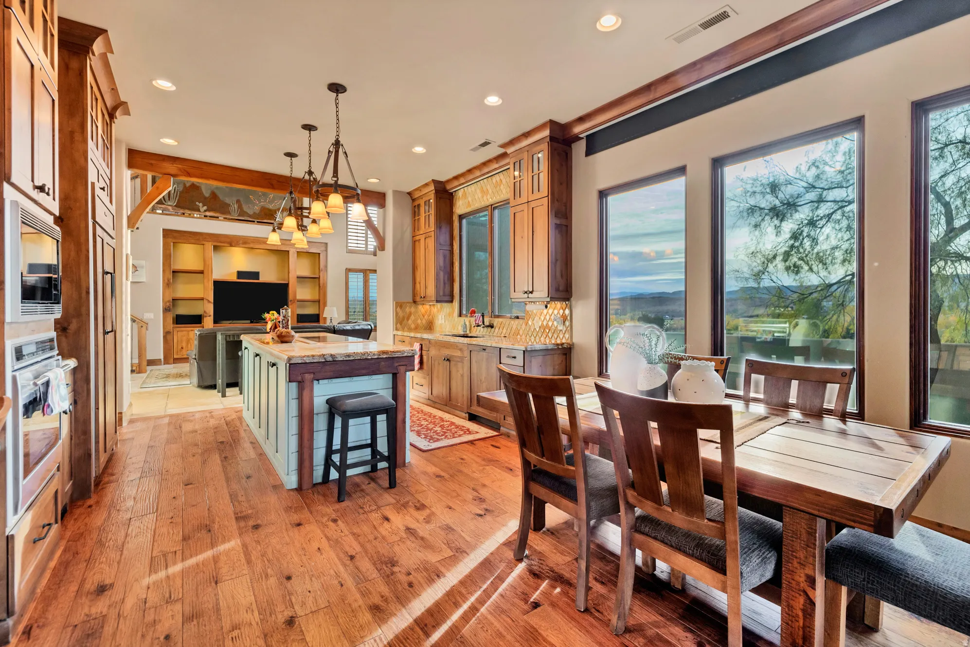 Kitchen with hanging light fixtures, a kitchen island, decorative backsplash, light stone countertops, and recessed lighting