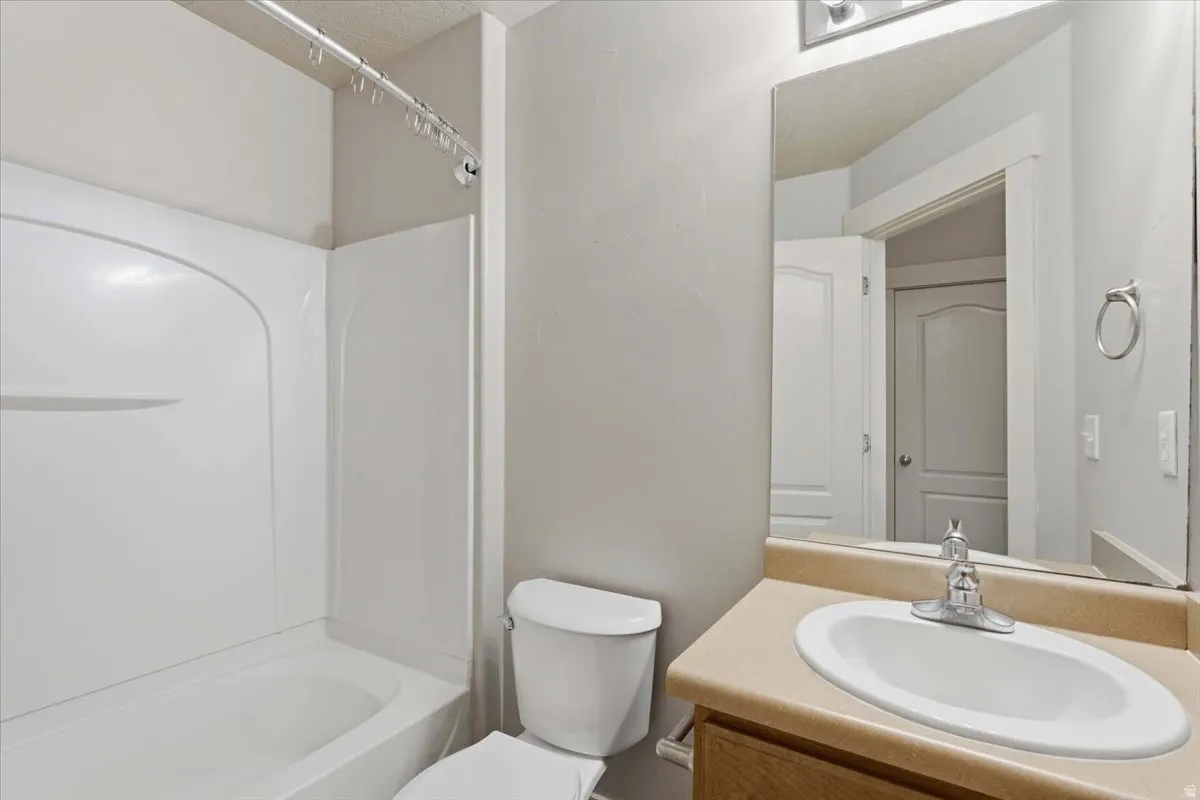 Bathroom with vanity, shower / tub combination, and a textured ceiling