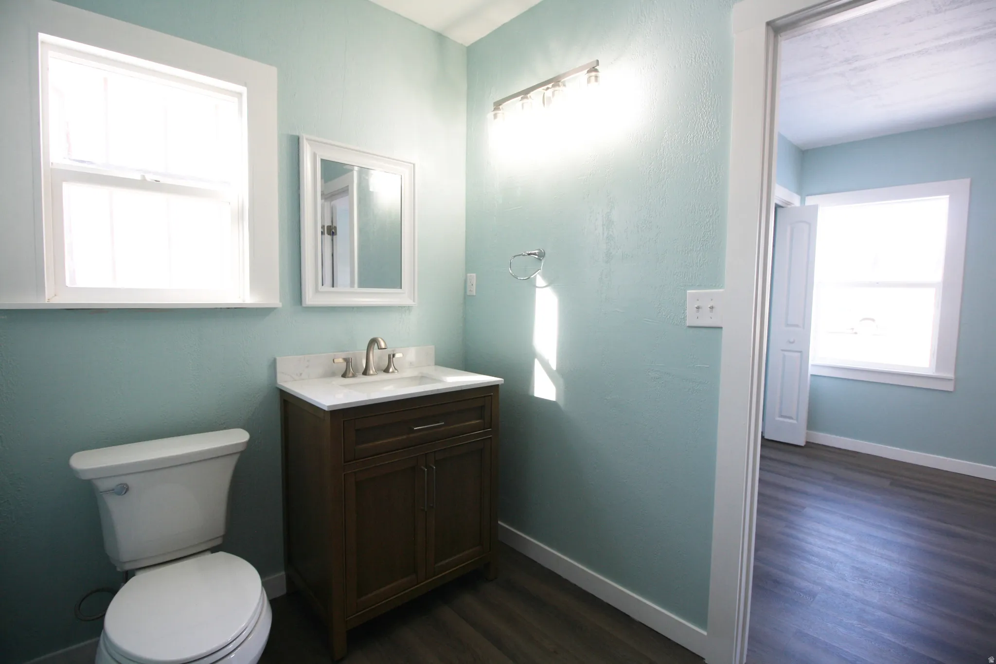Master en-suite Bathroom featuring healthy amount of natural light, vanity, and dark wood finished floors