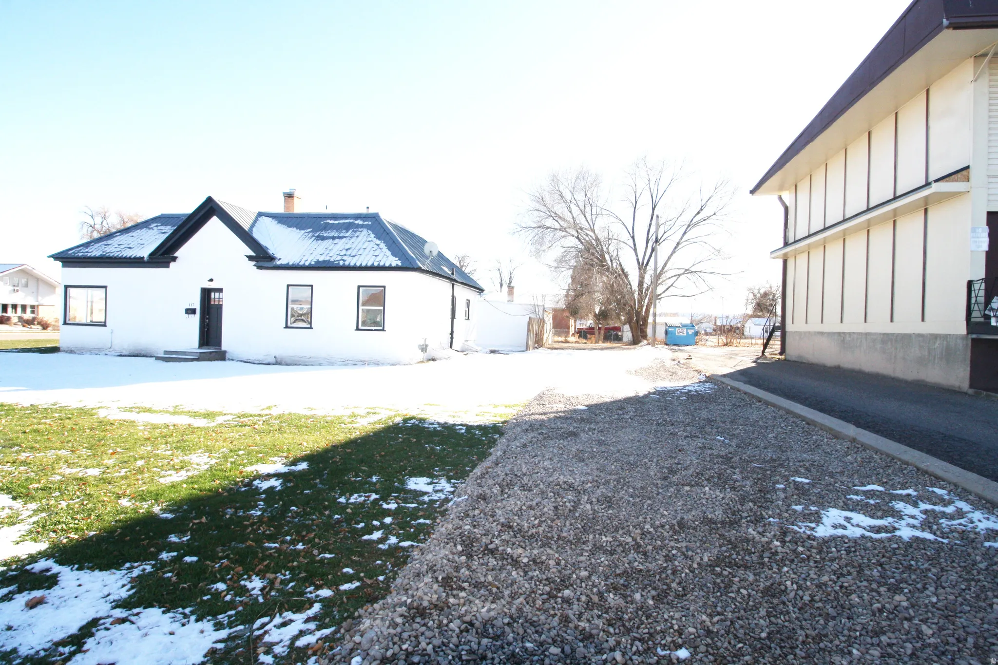 View of snowy exterior featuring board and batten siding and a yard