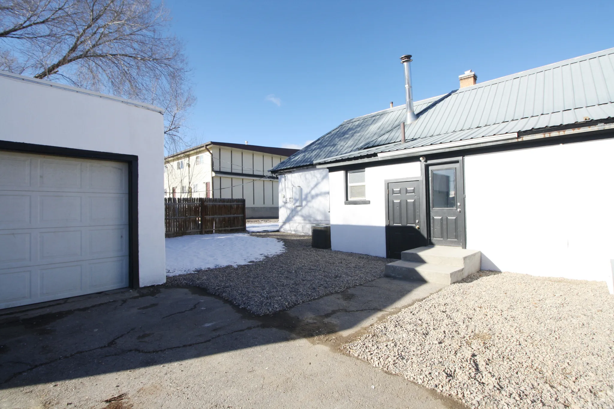 Entrance to property featuring a metal roof, a chimney, and stucco siding